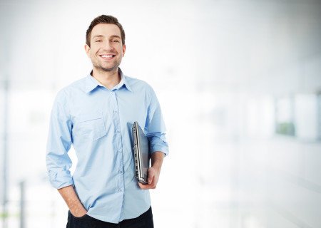 Handsome businessman with laptop standing
